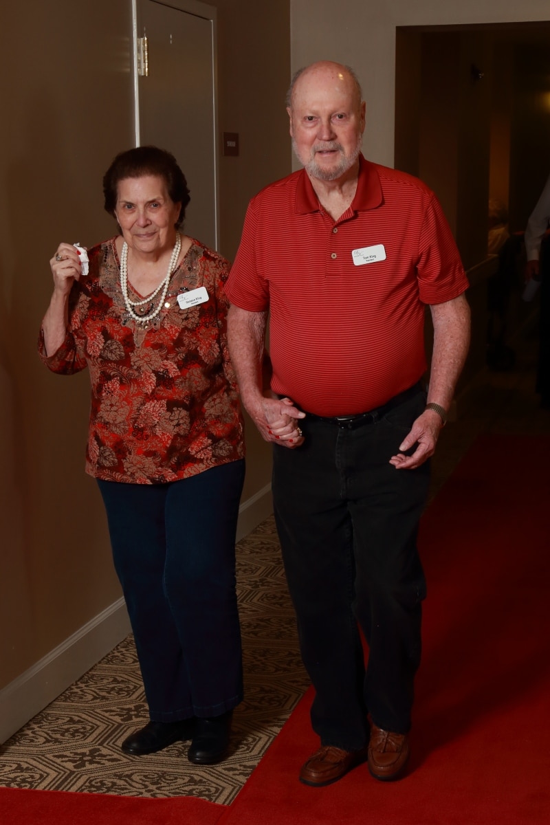 A senior living resident couple holding hands walking into an event
